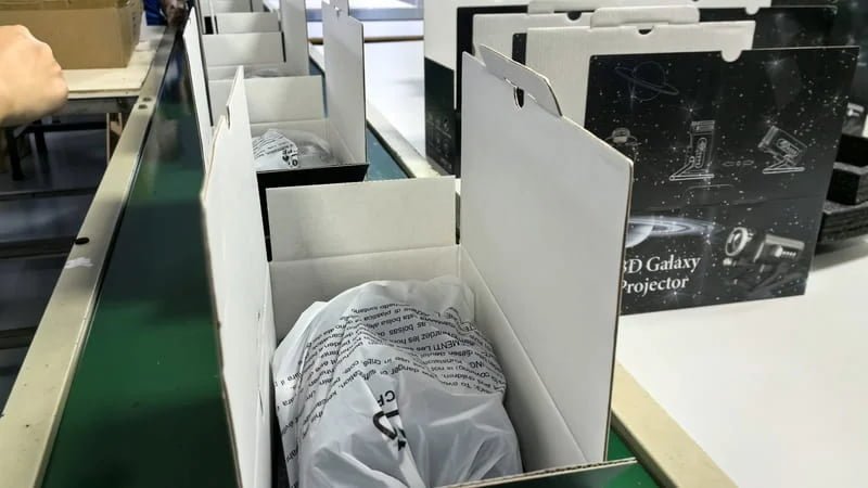 Star projector units being placed into retail boxes during packing